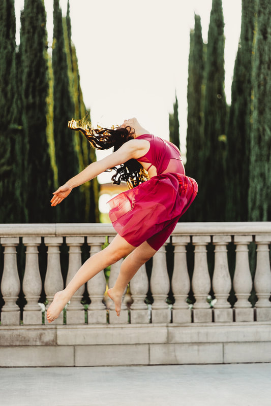 A dancer leaps forward leading with her torso rising several feet off the ground on a San Ramon walkway.