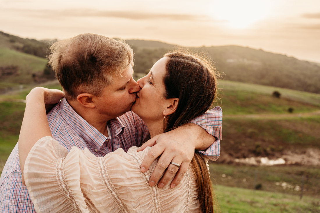 A mother and father kiss during a quiet moment during their Pleasanton family portrait photoshoot.