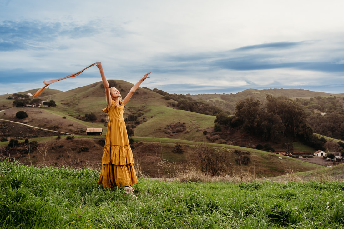 An 11 year old girl dances with a pink ribbon during family pictures in the Pleasanton hills.